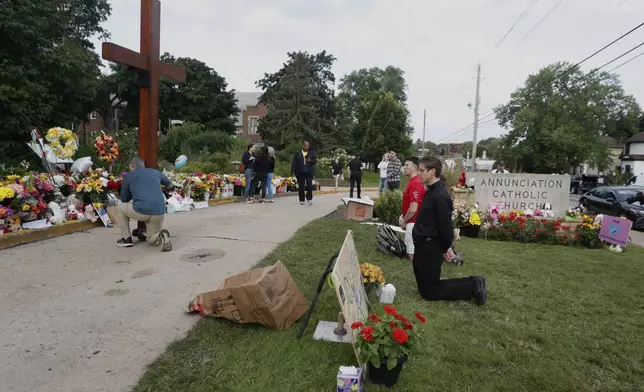 People visit a make-shift memorial at Annunciation Catholic Church after the Wednesday's shooting at the school, Friday, Aug. 29, 2025, in Minneapolis. (AP Photo/Bruce Kluckhohn)