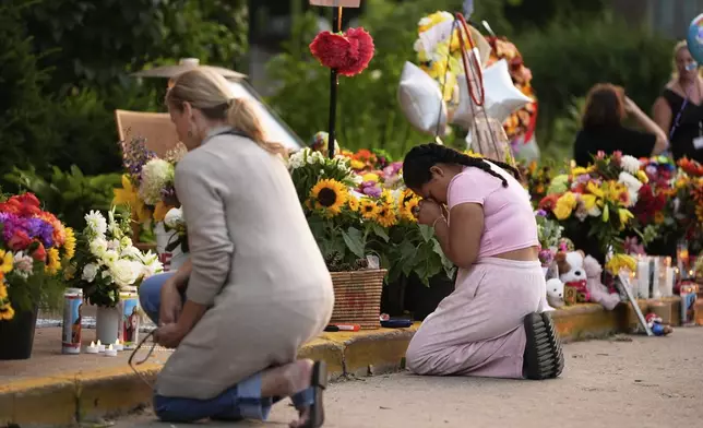 People pray at a memorial at Annunciation Catholic Church after Wednesday's school shooting, Thursday, Aug. 28, 2025, in Minneapolis. (AP Photo/Abbie Parr)