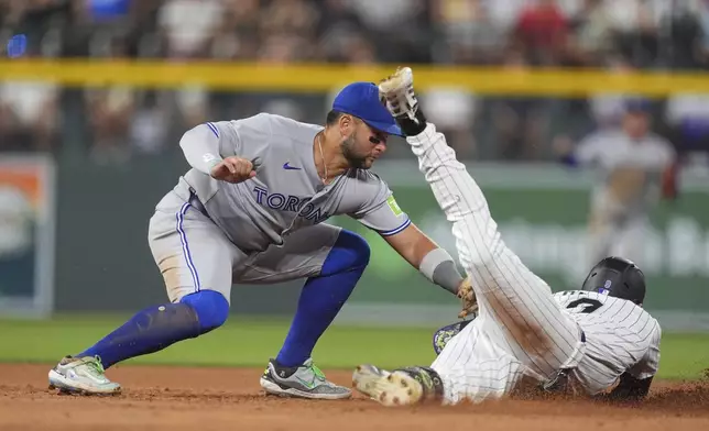 Toronto Blue Jays shortstop Bo Bichette, left, tags out Colorado Rockies' Brenton Doyle at second base as he tries to stretch a single into a double in the seventh inning of a baseball game Tuesday, Aug. 5, 2025, in Denver. (AP Photo/David Zalubowski)