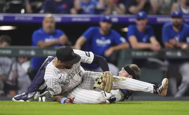 Colorado Rockies third baseman Warming Bernabel, front, collides with catcher Hunter Goodman while pursuing a foul ball off the bat of Toronto Blue Jays' Alejandro Kirk in the ninth inning of a baseball game Tuesday, Aug. 5, 2025, in Denver. (AP Photo/David Zalubowski)