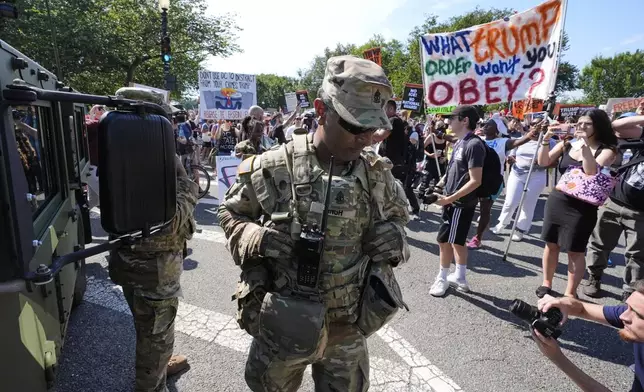 A first sergeant with the District of Columbia National Guard watches as activists protest President Donald Trump's federal takeover of policing of the District of Columbia, Saturday, Aug. 16, 2025, in Washington. (AP Photo/Alex Brandon)