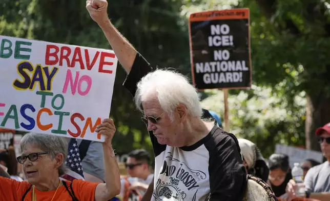 Activists carry signs during a protest against President Donald Trump's federal takeover of policing of the District of Columbia, Saturday, Aug. 16, 2025, in Washington. (AP Photo/Alex Brandon)