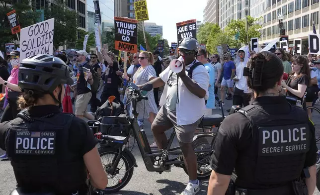 Secret Service police officers watch as activists carrying signs march to the White House to protest President Donald Trump's federal takeover of policing of the District of Columbia, Saturday, Aug. 16, 2025, in Washington. (AP Photo/Alex Brandon)