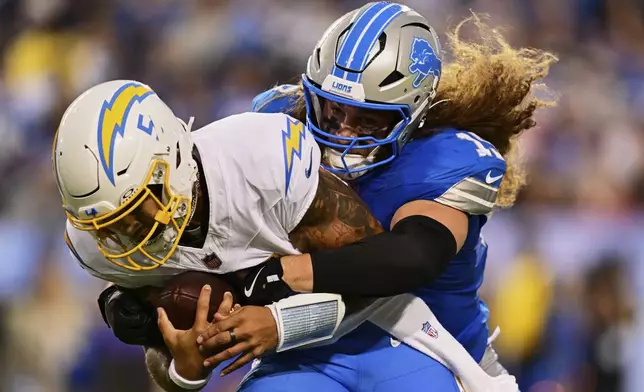 Detroit Lions linebacker Grant Stuard, right, sacks Los Angeles Chargers quarterback Trey Lance, left, in the first half of the Pro Football Hall of Fame NFL preseason game Thursday, July 31, 2025, in Canton, Ohio. (AP Photo/David Dermer)