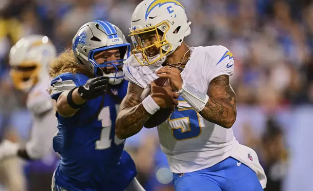 Detroit Lions linebacker Grant Stuard, left, pursues Los Angeles Chargers quarterback Trey Lance (5) in the first half of the Pro Football Hall of Fame NFL preseason game Thursday, July 31, 2025, in Canton, Ohio. (AP Photo/David Dermer)
