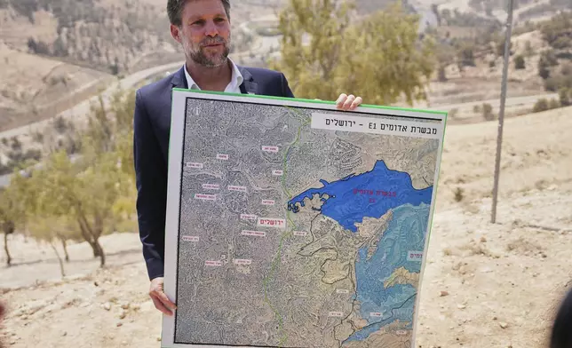 CORRECTS DAY Israeli Finance Minister Bezalel Smotrich holds a map that shows the E1 settlement project during a press conference near the settlement of Maale Adumim, in the Israeli-occupied West Bank, Thursday, Aug. 14, 2025. (AP Photo/Ohad Zwigenberg)