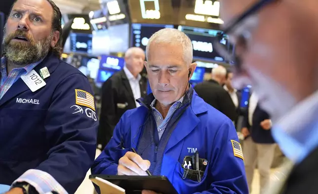 Timothy Nick, center, and Michael Pistillo, Jr. work on the floor at the New York Stock Exchange in New York, Wednesday, July 30, 2025. (AP Photo/Seth Wenig)