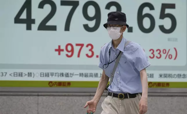 A person walks in front of an electronic stock board showing Japan's Nikkei index at a securities firm Tuesday, Aug. 12, 2025, in Tokyo. (AP Photo/Eugene Hoshiko)