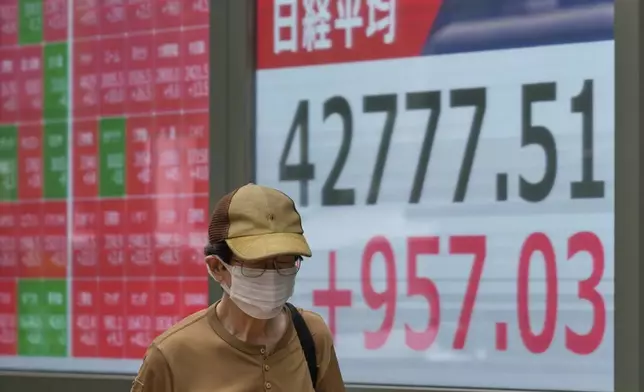 A person walks in front of an electronic stock board showing Japan's Nikkei index at a securities firm Tuesday, Aug. 12, 2025, in Tokyo. (AP Photo/Eugene Hoshiko)