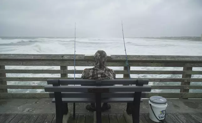 Sebastian Kettner fishes on Jennette's Pier as waves from Hurricane Erin crash ashore in Nags Head, N.C., Thursday, Aug. 21, 2025. (AP Photo/Allen G. Breed)