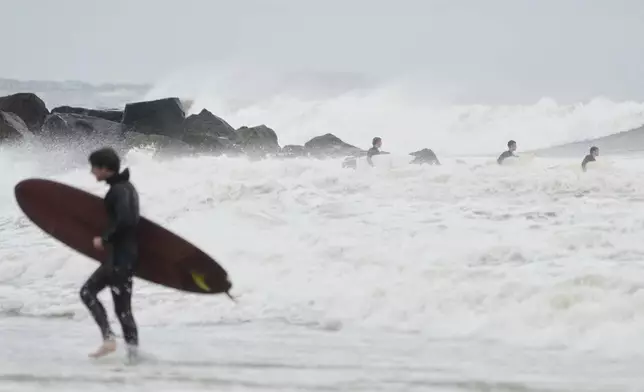 Surfers try to get in the water, past big waves bolstered by Hurricane Erin, at Rockaway Beach in the Queens borough of New York, Thursday, Aug. 21, 2025. (AP Photo/Seth Wenig)