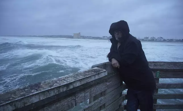 A man smokes a cigarette at the end of Jennette's Pier as waves from Hurricane Erin crash ashore in Nags Head, N.C., on Thursday, Aug. 21, 2025. (AP Photo/Allen G. Breed)