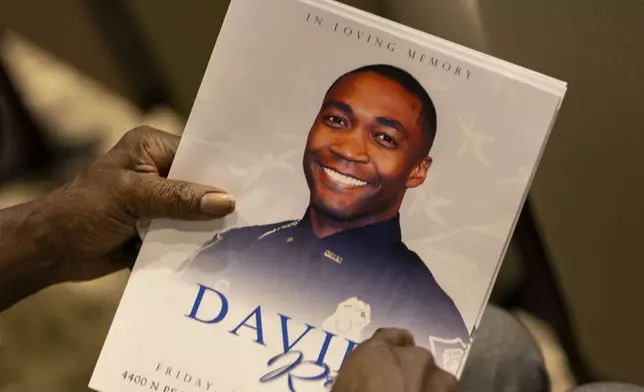 An attendee holds a program for the funeral of DeKalb County Police Officer David Rose, who was killed while responding to a shooting at the CDC, at First Baptist Church Atlanta, Friday, Aug. 22, 2025, in Atlanta. (Arvin Temkar/Atlanta Journal-Constitution via AP)