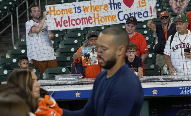 Fans hold a sign as Houston Astros third baseman Carlos Correa signs autographs during batting practice before a baseball game against the Boston Red Sox Monday, Aug. 11, 2025, in Houston. (AP Photo/David J. Phillip)