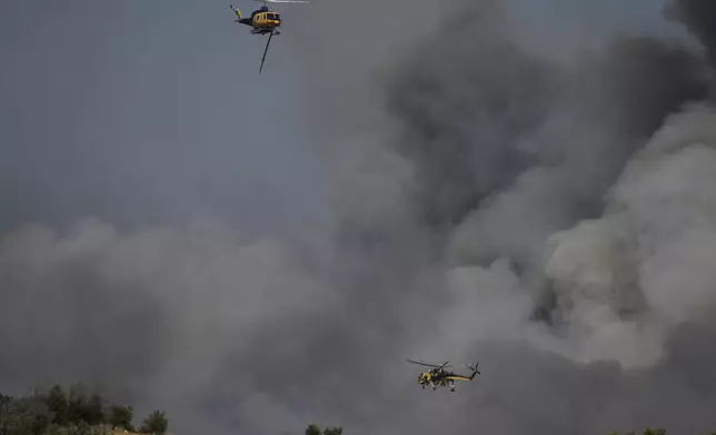 Firefighting helicopters drop water on a fire at Keratea, outskirt of Athens, on Friday, Aug. 8, 2025. (AP Photo/Thanassis Stavrakis)
