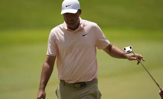 Scottie Scheffler hands his putter to his caddie on fourth green during the first round of the St. Jude Championship golf tournament Thursday, Aug. 7, 2025, in Memphis, Tenn. (AP Photo/George Walker IV)