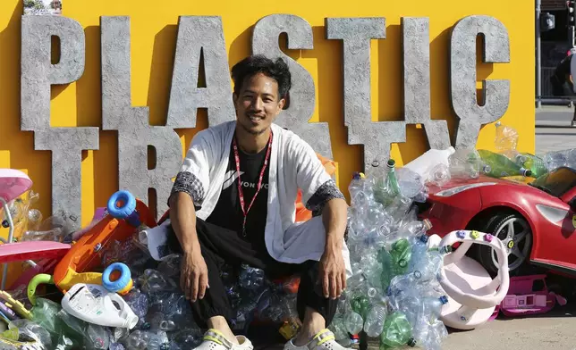 Benjamin Von Wong, a Canadian artist and activist, poses in front of a sculpture that he designed in front of the United Nations office in Geneva, Switzerland, Monday, Aug. 11, 2025. (AP Photo/ Jennifer McDermott)