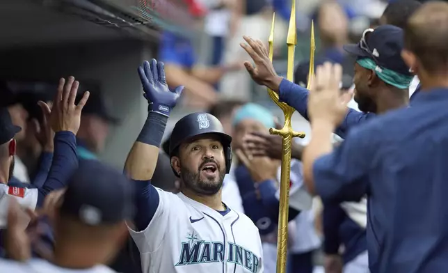 Seattle Mariners' Eugenio Suárez celebrates in the dugout his two RBI home run off Chicago White Sox starting pitcher Davis Martin during the fourth inning of a baseball game, Tuesday, Aug. 5, 2025, in Seattle. (AP Photo/John Froschauer)