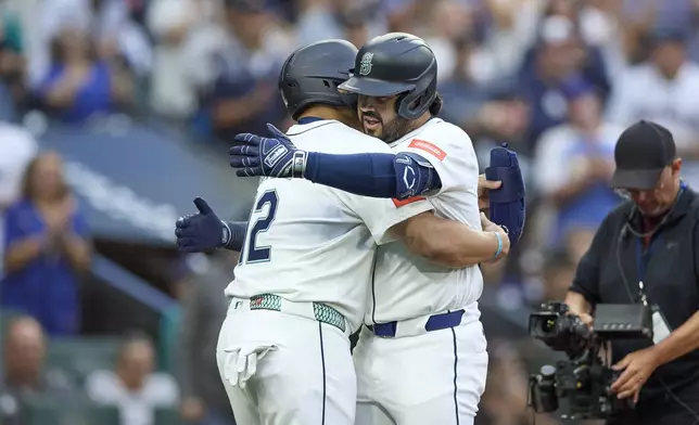 Seattle Mariners' Eugenio Suárez, right, hugs Josh Naylor, left, after both scored on Suárez's two RBI home run off Chicago White Sox starting pitcher Davis Martin during the fourth inning of a baseball game, Tuesday, Aug. 5, 2025, in Seattle. (AP Photo/John Froschauer)