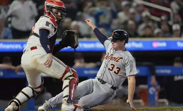 Detroit Tigers' Colt Keith (33) slides past Minnesota Twins catcher Ryan Jeffers, left, to score during the 11th inning of a baseball game Thursday, Aug. 14, 2025, in Minneapolis. (AP Photo/Abbie Parr)