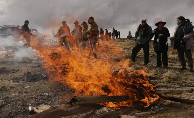People burn offerings observing the month of Pachamama, or Mother Earth, performing an ancient tradition to ask for a good harvest, on La Cumbre, a mountain considered sacred on the outskirts of La Paz, Bolivia, Friday, Aug. 1, 2025. (AP Photo/Juan Karita)