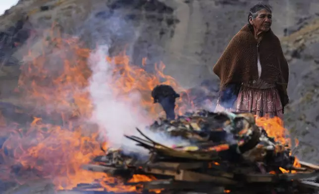 A woman burn offerings observing the month of Pachamama, or Mother Earth, performing an ancient tradition to ask for a good harvest, on La Cumbre, a mountain considered sacred on the outskirts of La Paz, Bolivia, Friday, Aug. 1, 2025. (AP Photo/Juan Karita)