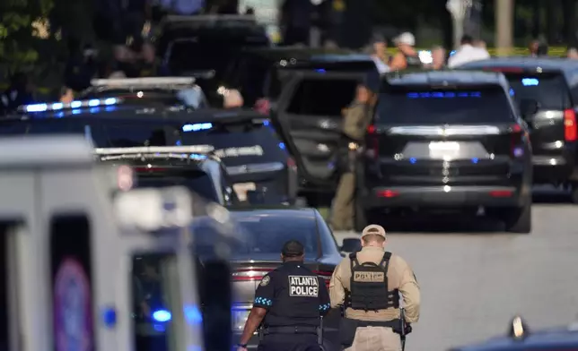 Police officers walk near the scene of shooting at the Emory University in Atlanta on Friday, Aug. 8, 2025. (AP Photo/Mike Stewart)