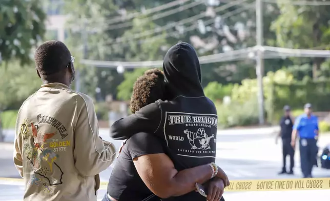 Pedestrians comfort each other after a shooting near the campuses of the U.S. Centers for Disease Control and Prevention and Emory University, Friday, Aug. 8, 2025, in Atlanta. (Jenni Girtman/Atlanta Journal-Constitution via AP)