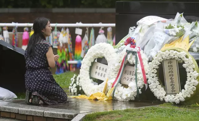 A woman offers prayer in the rain at the Atomic Bomb Hypocenter Park, as Japan commemorates the 80th anniversary of the day an atomic bomb was dropped on its southwestern city, in Nagasaki, Japan Saturday, Aug. 9, 2025.(AP Photo/Eugene Hoshiko)