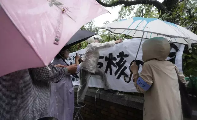 People put up a banner, ahead of a public ceremony to commemorate the 80th anniversary of the day an atomic bomb was dropped on Nagasaki, at the Atomic Bomb Hypocenter Park in Nagasaki, Japan Saturday, Aug. 9, 2025. The banner, partly seen, reads: "Nuclear." (AP Photo/Eugene Hoshiko)