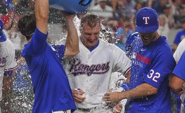Texas Rangers' Josh Jung, center, is doused after hitting a home run during the 10th inning of a baseball game against the New York Yankees, Monday, Aug. 4, 2025, in Arlington, Texas. (AP Photo/LM Otero)