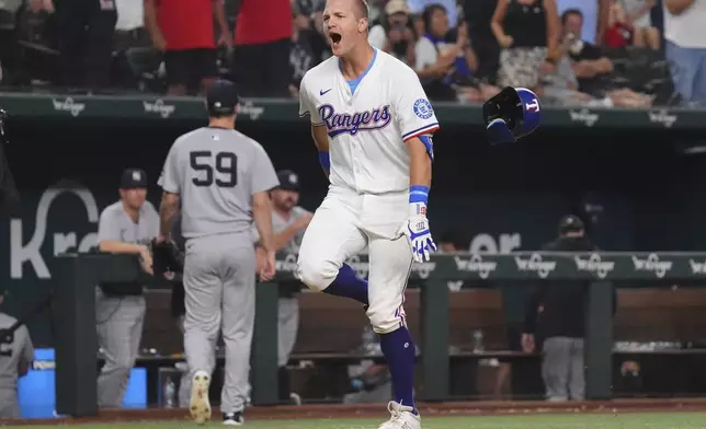 Texas Rangers' Josh Jung, right, celebrates after his home run as New York Yankees pitcher Jake Bird (59) walks to the dugout during the 10th inning of a baseball game Monday, Aug. 4, 2025, in Arlington, Texas. (AP Photo/LM Otero)