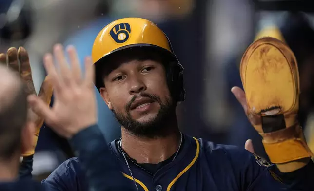 Milwaukee Brewers' Blake Perkins (16) celebrates scoring off the bat of Christian Yelich's RBI-single against the Atlanta Braves in the third inning of a baseball game, Tuesday, Aug. 5, 2025, in Atlanta. (AP Photo/Mike Stewart)