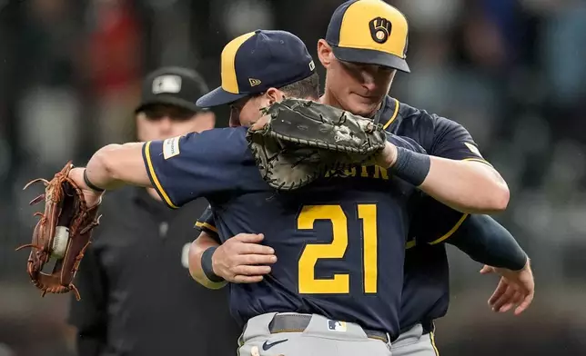 Milwaukee Brewers' Caleb Durbin (21) embraces Andrew Vaughn (28) after a baseball game against the Atlanta Braves, Tuesday, Aug. 5, 2025, in Atlanta. (AP Photo/Mike Stewart)