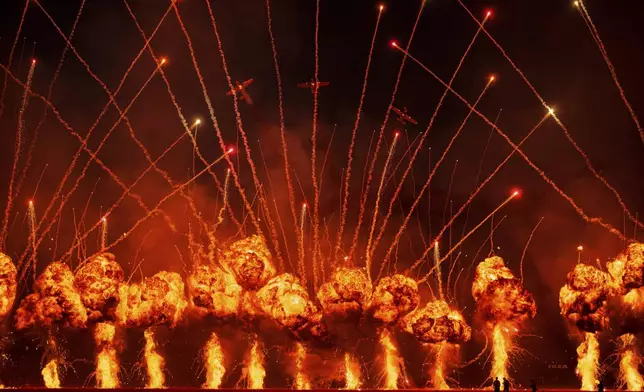 Pyrotechnics go off as the Air Bandits aerobatic team, led by Lithuanian pilot Jurgis Kairys, performs above the runway of the Aurel Vlaicu airport, at the end of the first day of the Bucharest International Air Show, BIAS 2025 in Bucharest, Romania, Saturday, Aug. 30, 2025. (AP Photo/Andreea Alexandru)