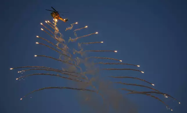 A Romanian Air Force helicopter gunship launches flares above the runway of the Aurel Vlaicu airport, on the first day of the Bucharest International Air Show, BIAS, in Bucharest, Romania, Saturday, Aug. 30, 2025. (AP Photo/Andreea Alexandru)