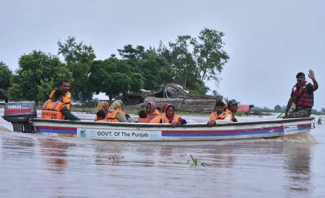 Villagers are evacuated by rescue workers from a flooded area in Dhoop Sarhi village in Kasur district, Pakistan, Tuesday, Aug. 26, 2025, due to the rising water level in Sutlej River, following neighboring India releasing water from overflowing dams. (AP Photo/K.M. Chaudary)