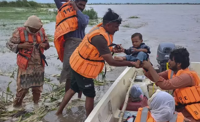 In this photo released by Pakistan's National Disaster Management Authority, rescue workers evacuate villagers from a low-lying area due to rising water level in the Sutlej River following neighbouring India released water from overflowing dams, in Bahawalnagar a district in Pakistan's Punjab province bordering India, Tuesday, Aug. 26, 2025. (Pakistan's National Disaster Management Authority via AP)