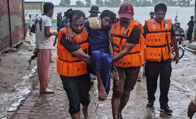 In this photo released by Pakistan's National Disaster Management Authority, rescue workers help a villager after evacuating him with others from a low-lying area due to rising water level in the Sutlej River following neighbouring India released water from overflowing dams, in Bahawalnagar a district in Pakistan's Punjab province bordering India, Tuesday, Aug. 26, 2025. (Pakistan's National Disaster Management Authority via AP)