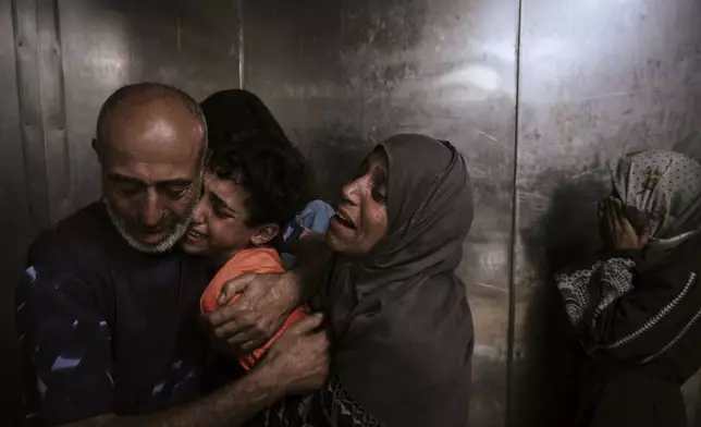 Raed Salem Aslyieh, left, from Jabaliya, hugs his relatives after the death of his son, Ahmed Raed Aslyieh, 18, who succumbed to injuries sustained in an Israeli strike that killed eight other family members four months earlier, worsened by a lack of proper treatment due to medicine shortages, at the morgue of Shifa Hospital in Gaza City, Wednesday, Aug. 6, 2025. (AP Photo/Jehad Alshrafi)