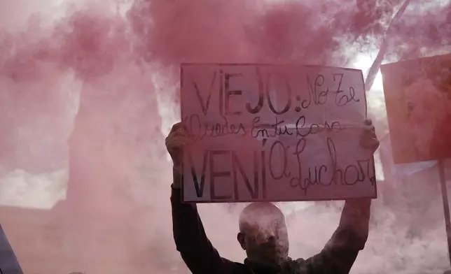 A protester holds a banner reading in Spanish, "Elderly, don't stay at home, come fight" during a weekly protest outside Congress demanding better pensions for retirees, in Buenos Aires, Argentina, Wednesday, Aug. 6, 2025. (AP Photo/Rodrigo Abd)