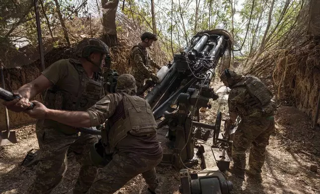Ukrainian servicemen of the 148th artillery brigade load ammunition into a M777 howitzer before firing towards Russian positions at the frontline in Zaporizhzhia region, Ukraine, on Thursday, Aug. 7, 2025. (AP Photo/Evgeniy Maloletka)