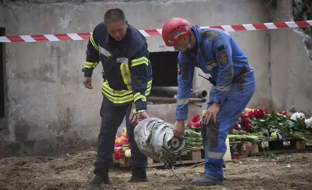 Searchers carry a fragment of the Russian missile that hit a multistory residential house on Thursday evening, in Kyiv, Ukraine, Friday, Aug. 1, 2025. (AP Photo/Efrem Lukatsky)