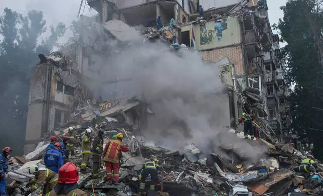 Rescuers work in a destroyed apartment building after a Russian missile attack in Kyiv, Ukraine, Thursday, July 31, 2025. (AP Photo/Efrem Lukatsky)