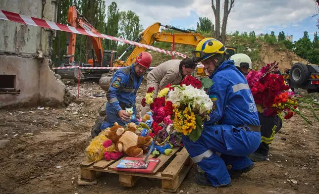 Rescuers lay toys and flowers on the site of Russia's Thursday night missile strike that hit a multistory residential house killing 31 civilians including five children in Kyiv, Ukraine, Friday, Aug. 1, 2025. (AP Photo/Efrem Lukatsky)