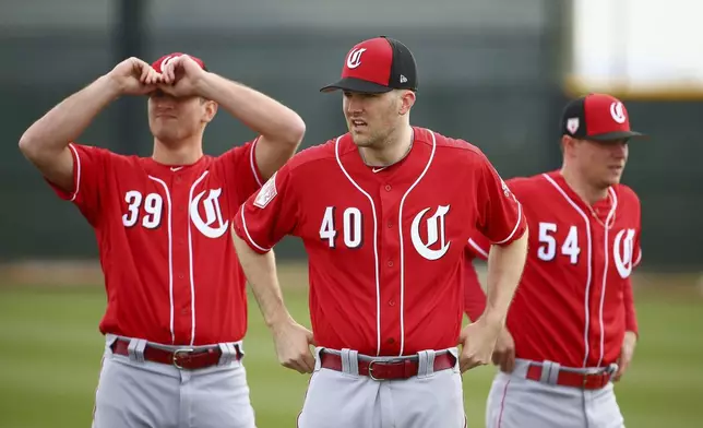 FILE - Cincinnati Reds pitchers Lucas Sims (39), Alex Wood (40) and Sonny Gray (54) pause between stretching exercises during workouts at the Reds spring training baseball facility, Feb. 13, 2019, in Goodyear, Ariz. (AP Photo/Ross D. Franklin, File)
