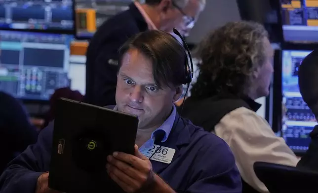 Trader Michael Milano left, works on the floor of the New York Stock Exchange, Monday, Aug. 18, 2025. (AP Photo/Richard Drew)