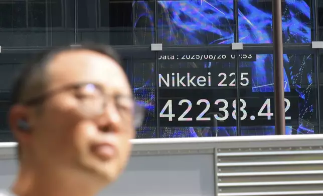 A person walks in front of an electronic stock board showing Japan's Nikkei index at a securities firm Tuesday, Aug. 26, 2025, in Tokyo. (AP Photo/Eugene Hoshiko)