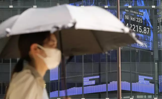 A person walks in front of an electronic stock board showing Japan's Nikkei index at a securities firm Tuesday, Aug. 26, 2025, in Tokyo. (AP Photo/Eugene Hoshiko)