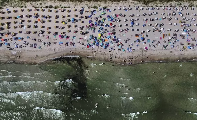 People spend the day at the beach of the Baltic Sea in Scharbeutz, northern Germany, Wednesday, Aug. 13, 2025. (AP Photo/Michael Probst)
